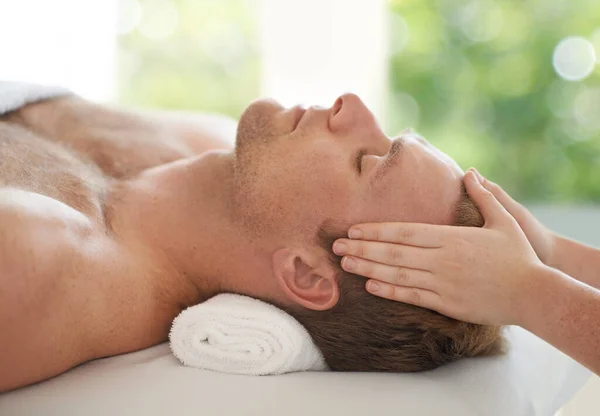 Lasciarsi sfuggire lo stress.... Colpo di un bell'uomo che si fa massaggiare la testa in una spa. — Foto Stock