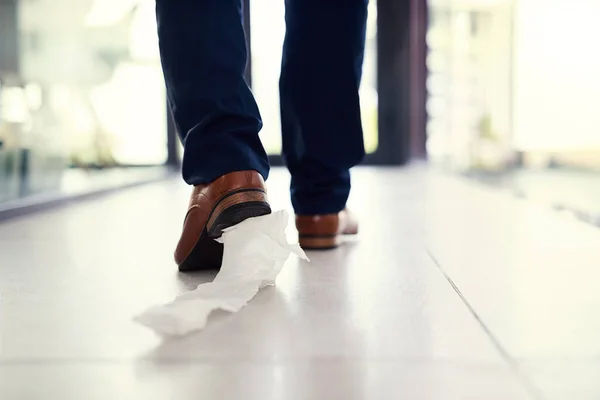 拖走了他的窘境一个商人站在办公室里，鞋子上贴着卫生纸拍的特写镜头. — 图库照片