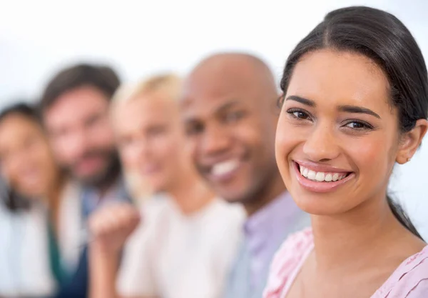 Shes bekam Ehrgeiz. Porträt einer attraktiven Geschäftsfrau, die in die Kamera lächelt und eine Reihe von Geschäftsleuten hinter sich hat. — Stockfoto