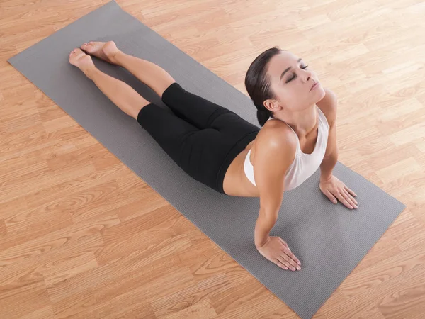 Cobra pose. Tiro de uma bela jovem fazendo ioga em um tapete de exercício. — Fotografia de Stock