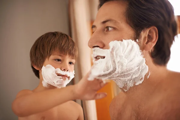 Hes got to learn some time. Shot of a little boy helping his father to shave. — Stock Photo, Image
