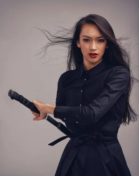 Kılıcını kınından çıkarıyor. Dövüş sanatları kıyafeti giymiş, elinde samuray kılıcı olan güzel bir kadının stüdyo portresi.. — Stok fotoğraf