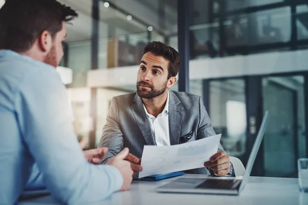 Análisis estadístico que cuentan una historia de éxito. Disparo de dos jóvenes hombres de negocios que utilizan un ordenador portátil mientras pasan por el papeleo juntos en una oficina moderna. — Foto de Stock