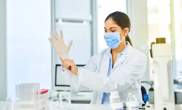 Prêt à plonger dans la recherche scientifique. Prise de vue d'un jeune scientifique portant des gants de protection dans un laboratoire. — Photo