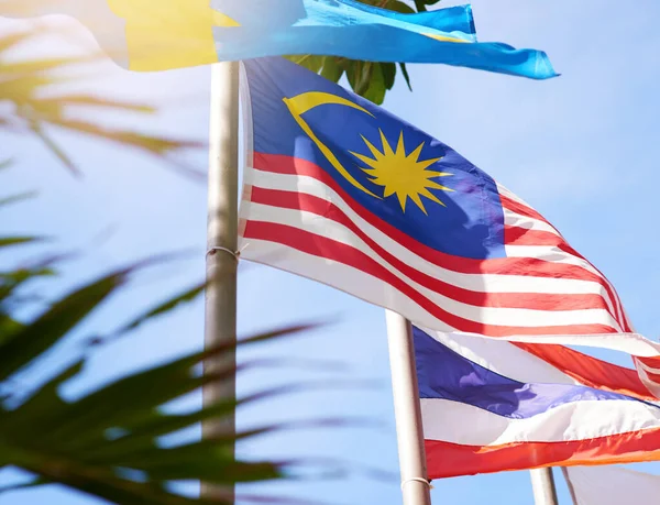 Fly it high, fly it proud. Shot of a Malaysian and Thailand flag blowing in the wind. — Stock Photo, Image