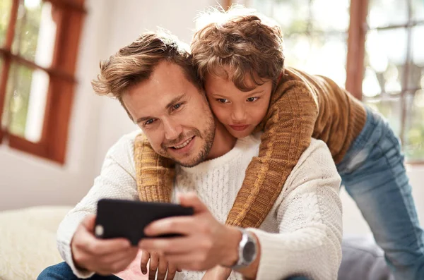 Většina vzpomínek našeho otce a syna je na tomto zařízení zdokumentována. Vystřižená fotka muže, jak si bere selfie se svým synem domů. — Stock fotografie