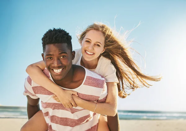 No puedes vencer a esa marca especial de amor veraniego. Foto de una feliz pareja joven disfrutando de un paseo a cuestas en la playa. —  Fotos de Stock