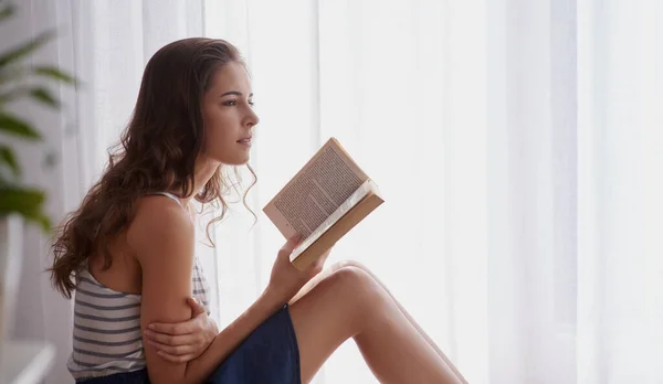 Alcune storie lasciano un'impressione duratura.... Colpo ritagliato di una giovane donna che legge un libro a casa. — Foto Stock