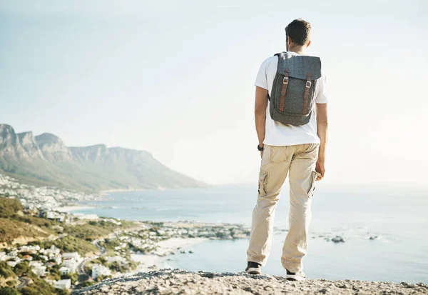 Neem de tijd om het uitzicht te bewonderen. Achteraanzicht van een onherkenbare jongeman die geniet van het uitzicht tijdens een wandeling in de bergen. — Stockfoto