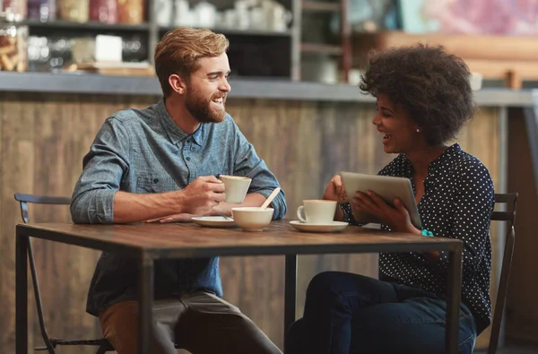 Ele fá-la rir. Tiro de um jovem casal usando um tablet digital juntos em uma data de café. — Fotografia de Stock