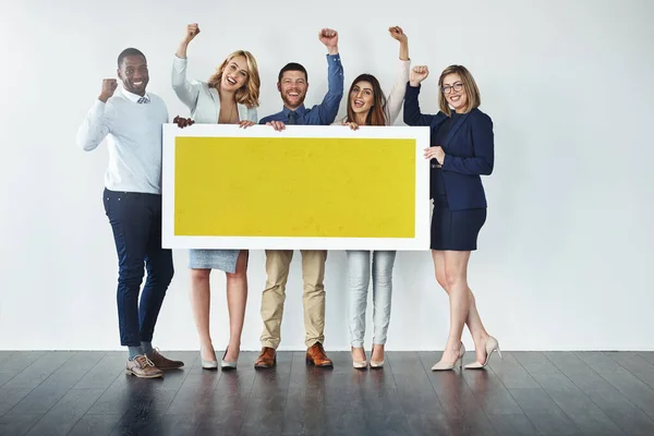 Isto merece todo o apoio que recebeste. Estúdio de um grupo de empresários segurando um cartaz amarelo em branco e aplaudindo. — Fotografia de Stock