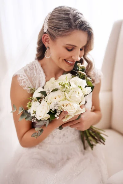 Pongamos este espectáculo en marcha. Foto recortada de una atractiva joven novia sentada sola en el vestidor y sosteniendo su ramo de flores. —  Fotos de Stock