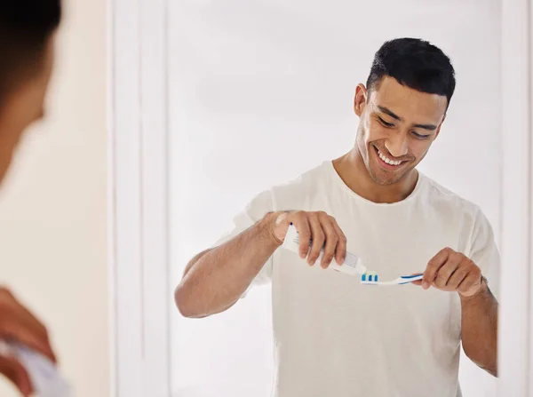 Dental hygiene is a must. Shot of a handsome young man standing alone in his bathroom and brushing his teeth in the morning. — Stock Photo, Image