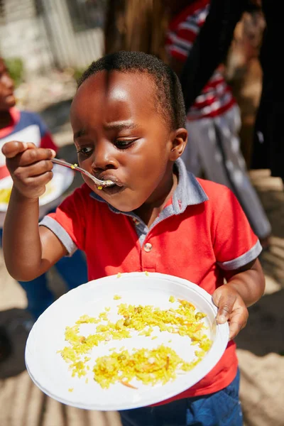 İşi bittikten sonra tabağında hiçbir şey kalmayacak. Bir gıda yardımında beslenen çocukların kırpılmış görüntüsü.. — Stok fotoğraf