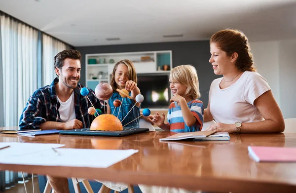 Elle nous emmène dans un voyage à travers la galaxie. Tournage d'une belle jeune famille travaillant ensemble sur un projet scientifique à la maison. — Photo