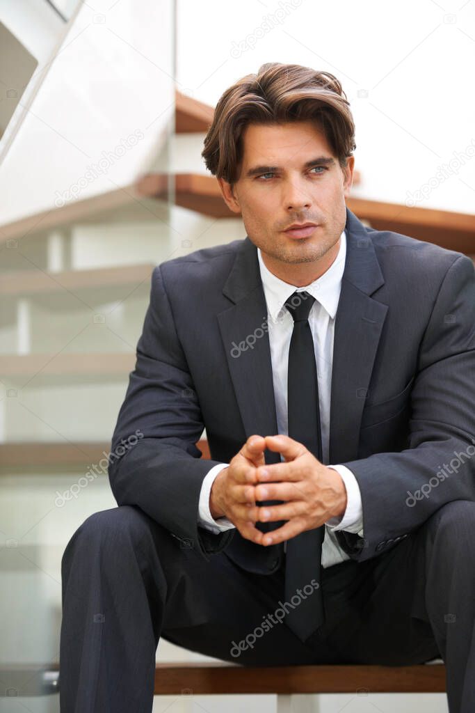 Planning his next business move. A handsome young businessman sitting on the stairs deep in thought.