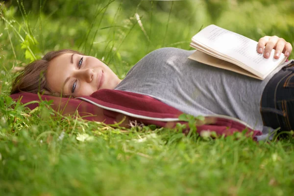Att hamna i en bra bok. Beskuren bild av en attraktiv ung kvinna på ett grönt fält. — Stockfoto
