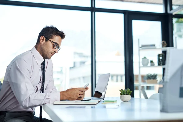 Ik weet precies wie ik moet bellen. Shot van een zakenman met behulp van zijn mobiele telefoon terwijl hij aan zijn bureau zit. — Stockfoto