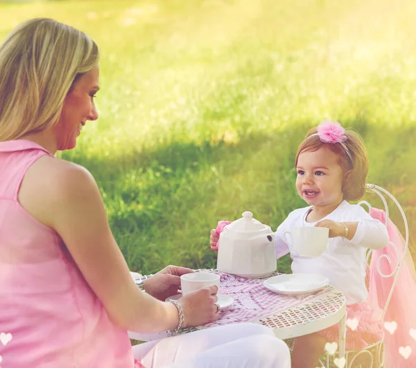 Let me pour you a cuppa. Shot of a mother and her cute little girl having a tea party on the lawn outside. — Stock Photo, Image