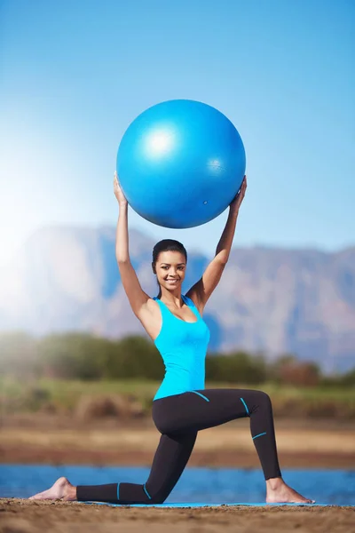 Reinventa tu cuerpo. Tiro de una mujer joven haciendo ejercicio con una pelota de ejercicio. — Foto de Stock
