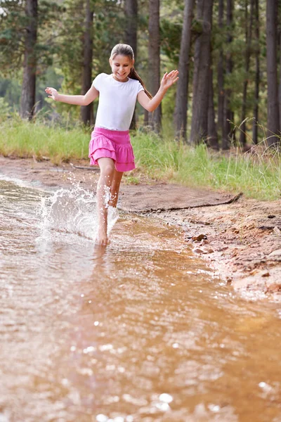 On s'éclabousse, c'est marrant. Une jolie petite fille qui court dans un ruisseau sauvage. — Photo