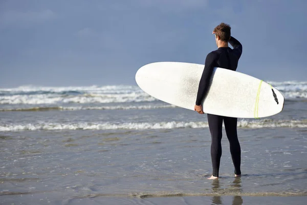 Dalgalarla kapışmaya hazır. Sörf yapmak üzere olan genç bir adamın fotoğrafı.. — Stok fotoğraf