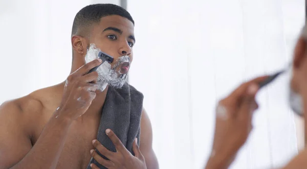 Estos son mis momentos de amor propio. Cortado tiro de un joven guapo de pie y usando su espejo del baño para afeitarse en la mañana. — Foto de Stock