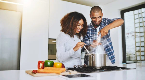 Litt krydder har aldri skadet noen. Skutt av et ungt par som lager mat sammen hjemme. – stockfoto