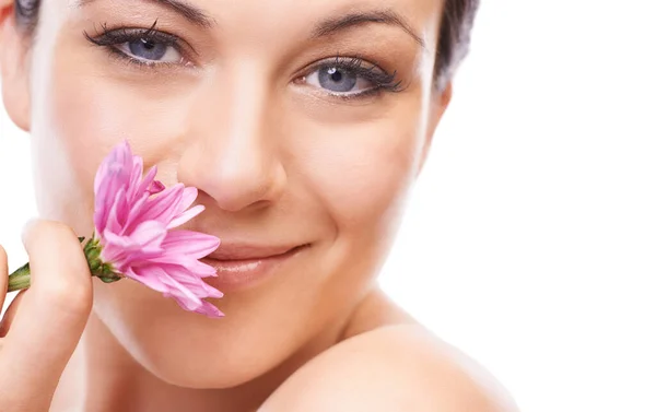 Friss, mint a virág. Egy bájos fiatal nő mosolyog a kamerába, miközben egy rózsaszín virágot szagolgat.. — Stock Fotó