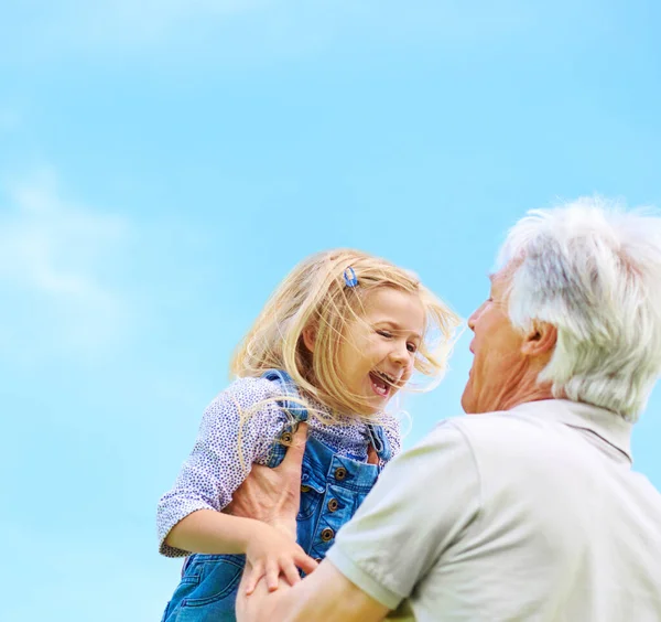 O avô sabe sempre como fazê-la rir. Tiro de um avô feliz levantando sua neta jovem. — Fotografia de Stock