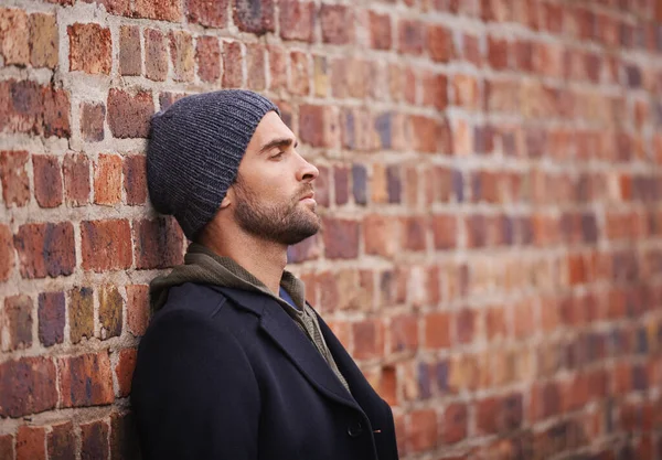 Style ville. Plan recadré d'un homme à la mode appuyé contre un mur de briques dans un cadre urbain. — Photo
