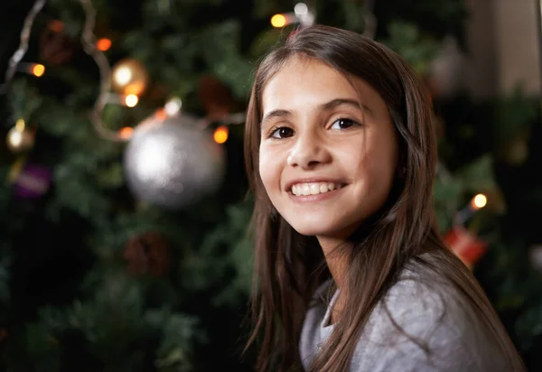 É uma época alegre do ano. Tiro de uma menina sentada perto de uma árvore de Natal. — Fotografia de Stock