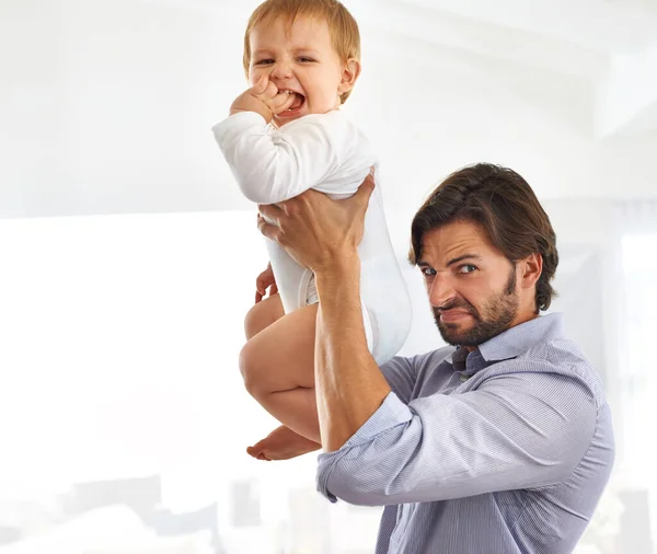 Às vezes, pode ser um trabalho sujo... Tiro de um belo pai segurando seu filho no ar enquanto faz uma cara. — Fotografia de Stock