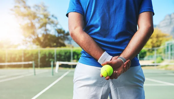Nunca se sabe a qué serviré después. Vista trasera de un jugador de tenis irreconocible que sostiene una pelota de tenis en una cancha al aire libre. —  Fotos de Stock