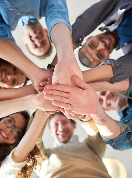 チームワークでそれを実現します。互いの上に自分の手を積ま同僚のグループの低角度ショット. — ストック写真