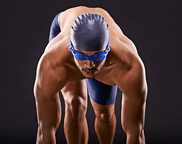 Haz que las vueltas cuenten. Captura de estudio de un apuesto nadador listo para zambullirse en el bloque de salida. —  Fotos de Stock