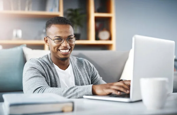 Я остаюсь на связи, чтобы ничего не пропустить. Портрет счастливого молодого человека с ноутбуком во время отдыха дома. — стоковое фото