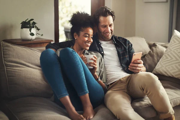 Cierra la puerta, deja el mundo afuera. Foto de una feliz pareja joven usando una tableta digital mientras se relaja en un sofá en su sala de estar en casa. — Foto de Stock