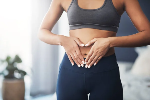 Tens de mostrar amor ao teu corpo. Tiro cortado de uma jovem mulher irreconhecível fazendo uma forma de coração em seu estômago em seu quarto. — Fotografia de Stock