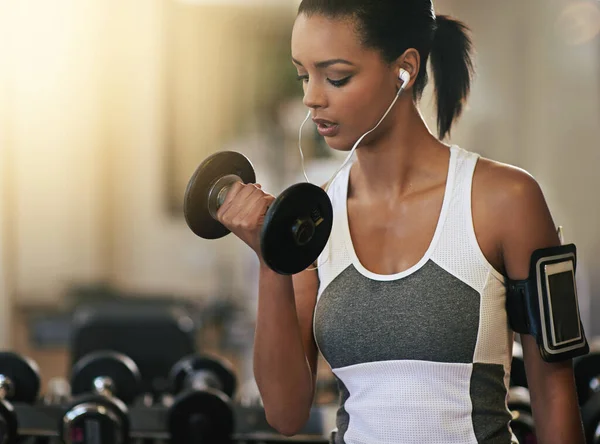 She never skips a gym session. Shot of a young woman working out with dumbbells at the gym. — Stock Photo, Image