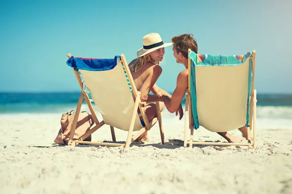 Simplemente no sería lo mismo sin ti. Vista trasera de una joven pareja sentada en tumbonas en la playa. — Foto de Stock