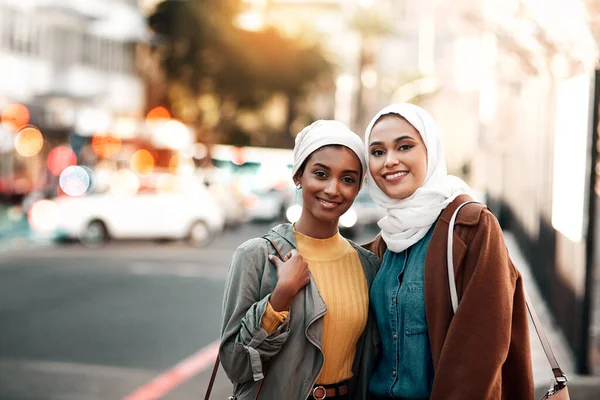 Amigos que viajam juntos, fiquem juntos. Tiro recortado de duas jovens mulheres atraentes vestindo lenços de cabeça e de pé juntos enquanto passeiam pela cidade juntos. — Fotografia de Stock