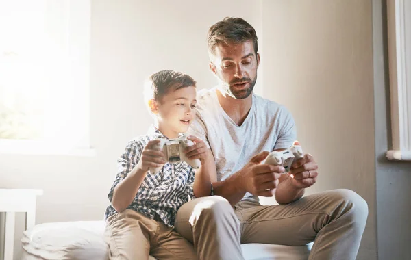 Mostrándole cómo jugar el juego. Recortado disparo de un niño y su padre jugando videojuegos. — Foto de Stock