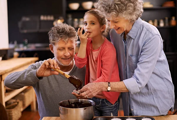 Mmm.. to jest takie dobre. Portret dziewczynki i jej dziadków piekących babeczki w kuchni. — Zdjęcie stockowe
