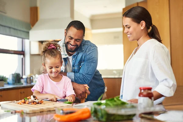 食べ物は愛で作られたときだけ味がよくなります。カップルと娘が台所で一緒に料理をしてる. — ストック写真