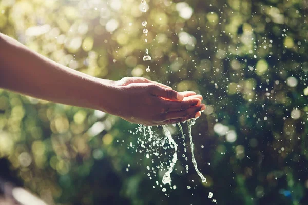 Refrescante salpicos. close-up tiro de um homem segurando as mãos sob uma corrente de água ao ar livre. — Fotografia de Stock