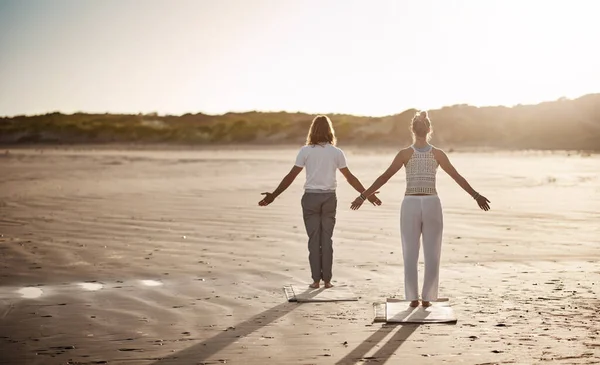 Jdi svou mírumilovnou cestou s jógou. Zadní snímek nerozpoznatelného páru, který cvičí jógu na pláži. — Stock fotografie