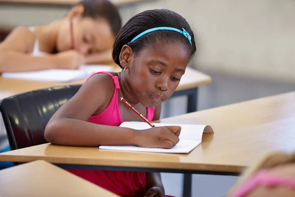 Buone abitudini di studio iniziano giovane. Una giovane ragazza in una classe concentrata sul suo test. — Foto Stock