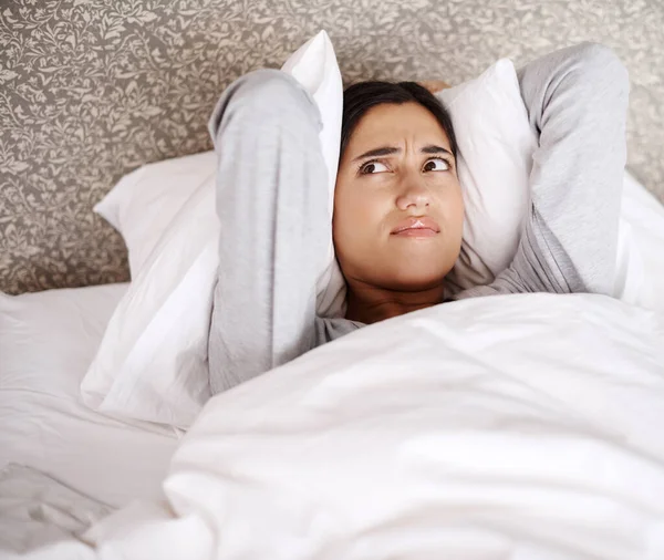 ¿Qué está haciendo ese ruido? Una joven que parece frustrada en la cama. —  Fotos de Stock