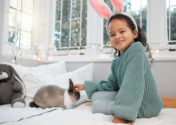 Schauen Sie, waren passend. Aufnahme eines entzückenden kleinen Mädchens, das auf ihrem Bett sitzt und sich mit ihrem Haustier Kaninchen zu Hause verbindet. — Stockfoto